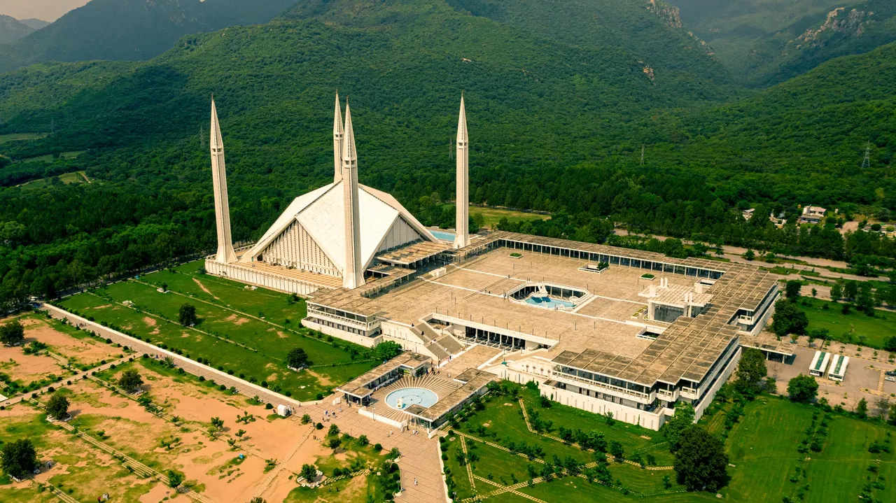 Stunning aerial shot of Shah Faisal Mosque surrounded by lush greenery in Islamabad, Pakistan.