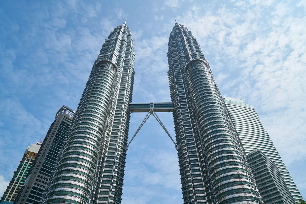 The iconic Petronas Twin Towers against a bright blue sky in Kuala Lumpur, Malaysia.