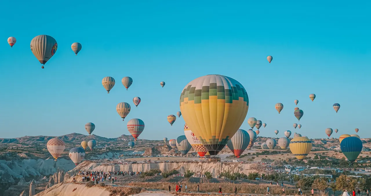 Vibrant hot air balloons soar over Cappadocia's unique landscape in Turkey.
