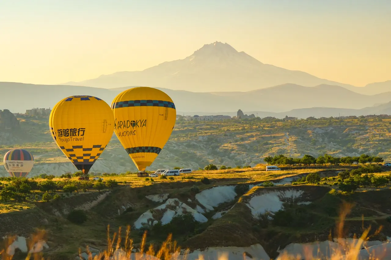 Captivating view of hot air balloons soaring over Cappadocia's unique landscape at sunrise, Türkiye.